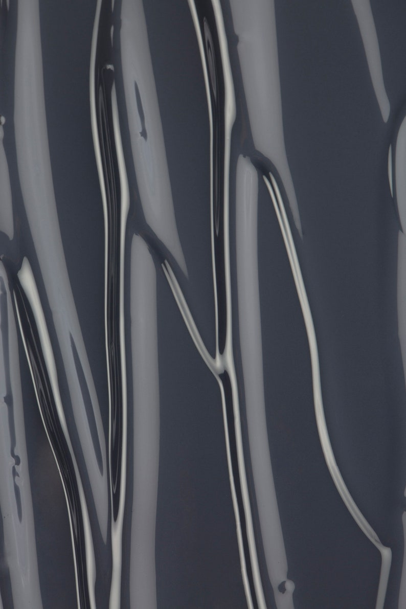 May include: Close-up of a dark gray, glossy, liquid with a smooth, flowing texture. The liquid has a slightly metallic sheen and creates a rippling effect.