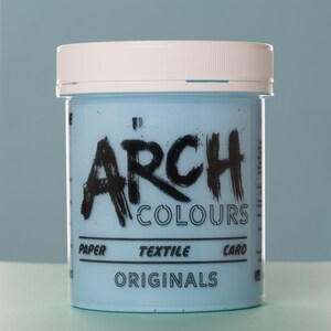 May include: A white plastic jar with a blue lid. The jar is labeled "Arch Colours" in black lettering. The jar also has the words "Paper, Textile, Card, Originals" printed on it.