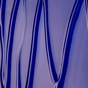May include: Close-up of a blue, glossy, liquid surface with wavy lines and a smooth, reflective texture.