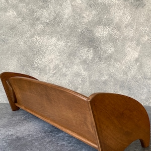 May include: A wooden sofa frame with a curved back and legs. The frame is made of a light brown wood and has a smooth finish.