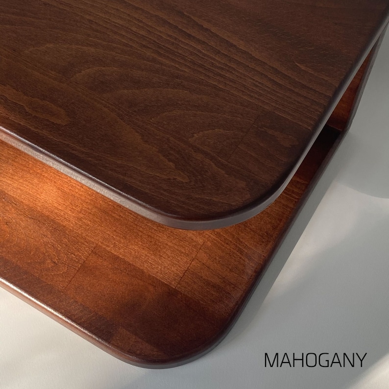 May include: Close-up of a two-tiered wooden coffee table with a rounded edge. The table is made of mahogany wood and has a rich brown color.