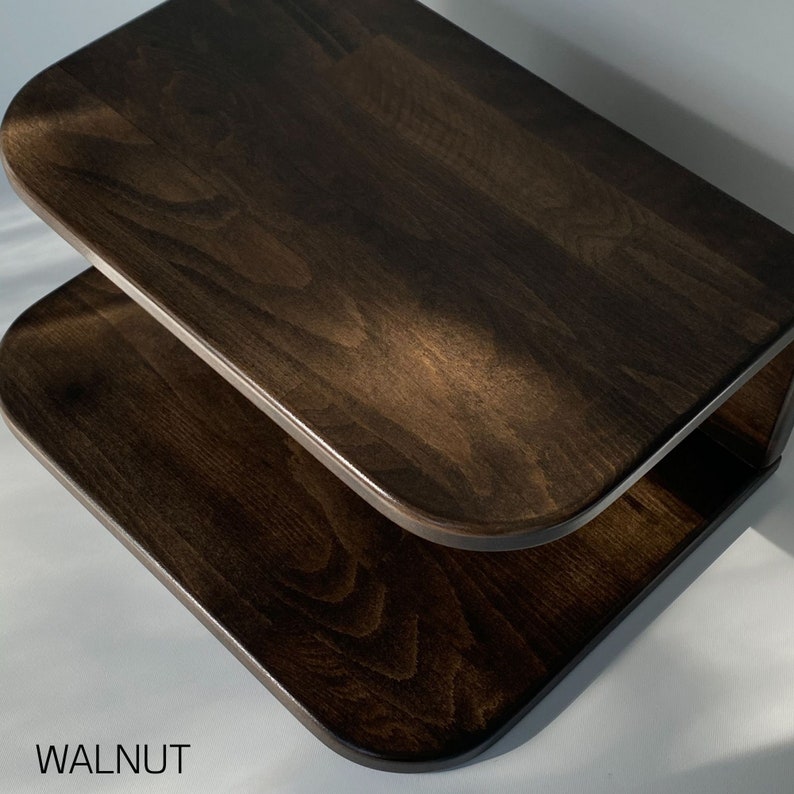 May include: A two-tiered wooden shelf with rounded edges, finished in a dark walnut stain. The shelf is mounted to a wall.