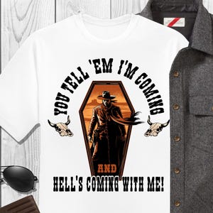 May include: White t-shirt with a graphic of a cowboy in a coffin, the text reads "YOU TELL 'EM I'M COMING AND HELL'S COMING WITH ME!". A gray button-up shirt, black sunglasses, and a brown wallet are also in the image.