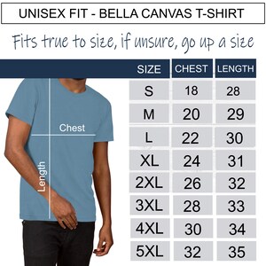 Op de afbeelding: Een lichtblauw Bella Canvas unisex T-shirt met een maattabel. De tabel toont borst- en lengtematen voor de maten S tot en met 5XL. De tekst luidt: "Valt normaal, bij twijfel een maat groter nemen."