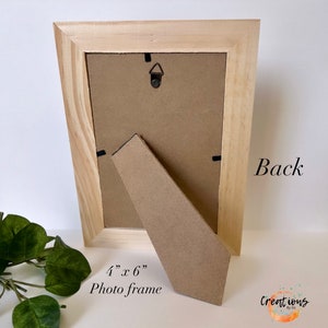 Pu&ograve; includere: Vista posteriore di una cornice in legno chiaro. La cornice misura 10 cm x 15 cm e ha un retro in cartone e un cavalletto. Il testo "Back" &egrave; visibile sulla cornice, insieme al testo "4" x 6" Photo frame".