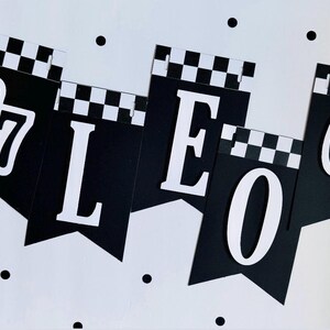 May include: Black and white banner with the word "LEO" and the number "67" in white. The top of each banner has a checkered pattern. Black polka dots are scattered on the white background.