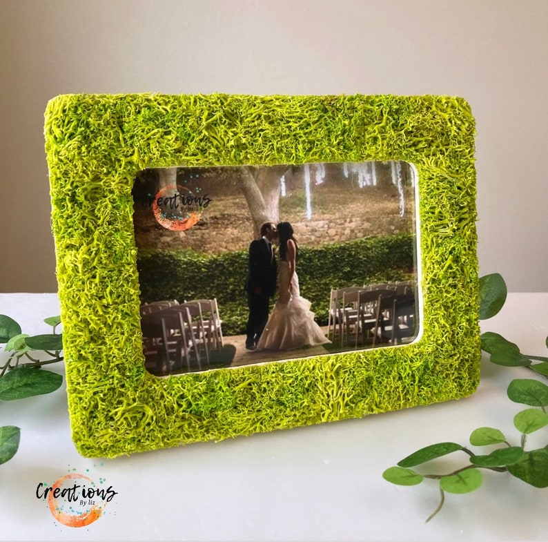 Pu&ograve; includere: Una cornice rettangolare con una vibrante texture verde simile al muschio. La cornice contiene una fotografia di matrimonio di una coppia che si bacia. La cornice ha il testo "Creations by Liz" in basso a sinistra.