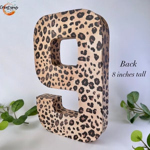 May include: A large number 9, 8 inches tall, with a leopard print pattern in shades of tan and brown. The number is free-standing and has a hollow interior. The word "Back" and the height are printed on the side.