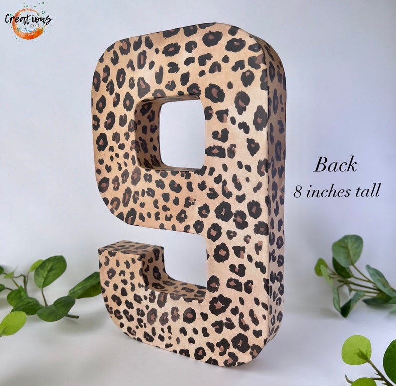 May include: A large number 9, 8 inches tall, with a leopard print pattern in shades of tan and brown. The number is free-standing and has a hollow interior. The word "Back" and the height are printed on the side.