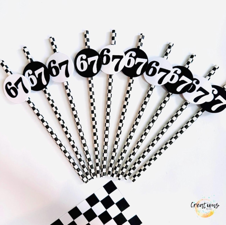 May include: A collection of black and white party decorations. Each decoration features a black circle with the number "67" in white, attached to a checkered straw. A checkered flag is also visible. The theme is racing.
