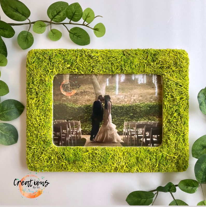 Pu&ograve; includere: Una cornice rettangolare con una vibrante texture verde muschio. La cornice contiene una fotografia di una coppia che si bacia a un matrimonio. La cornice &egrave; decorata con il testo "Creations by Liz".