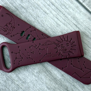 Puede incluir: Dos correas de reloj granate con diseños celestiales. Una correa tiene una hebilla, mientras que la otra presenta patrones de sol, luna y constelaciones. Las correas están hechas de un material flexible.