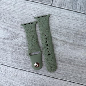 K&ouml;nnte beinhalten: Ein olivgr&uuml;nes Silikon-Uhrenarmband mit einem eingravierten Muster aus himmlischen Elementen wie Sonnen, Monden, Sternen, Schlangen und Motten. Das Armband besteht aus zwei Teilen mit einem Metallstiftverschluss und Standardanschl&uuml;ssen.