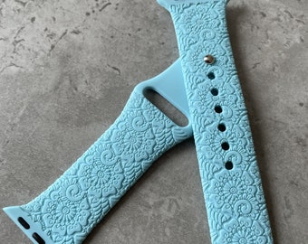 May include: A light blue silicone Apple Watch band with a floral pattern.