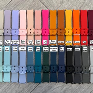 May include: A collection of colorful watch bands in various shades, including beige, pink, blue, green, orange, and black. Each band is labeled with its color name, such as "Stone Beige," "Hot Pink," and "Red."