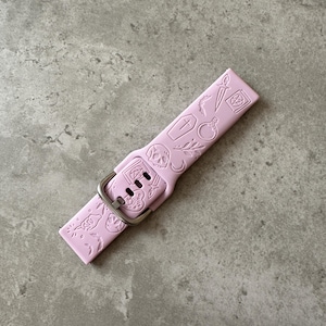 May include: A pink silicone watch band with a silver buckle. The band is decorated with a variety of small, embossed designs, including a skull, a coffin, a dagger, and a potion bottle.