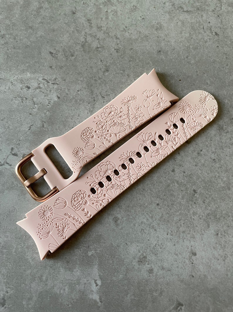 May include: A pink silicone watch strap with a floral pattern. The strap has a rose gold buckle.