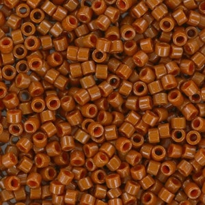 May include: A close-up image of a large quantity of small, brown, cylindrical beads. The beads are arranged in a random pattern, creating a textured surface.