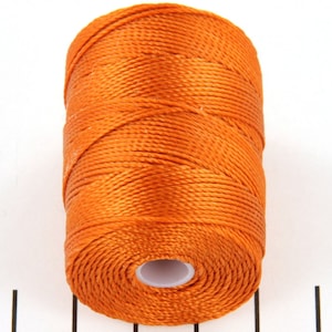 May include: A spool of orange thread.