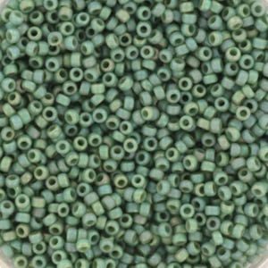 May include: A close-up image of a large quantity of small, round, green glass beads. The beads have a slightly iridescent finish, giving them a subtle shimmer.
