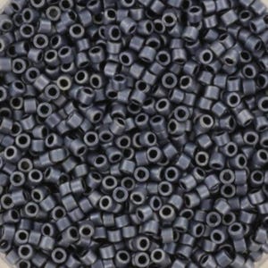 Puede incluir: Primer plano de un montón de pequeñas cuentas cilíndricas de color gris oscuro. Cada cuenta tiene un agujero en el centro. Las cuentas están densamente empaquetadas, llenando el marco.