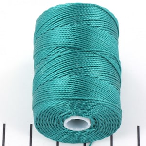 May include: A spool of teal-colored nylon thread. The thread is tightly wound, showing a textured surface. The spool has a white core. Ideal for crafting, jewelry making, or other creative projects.