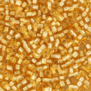 May include: A close-up image of a large quantity of small, gold-colored glass beads. The beads are cylindrical in shape and have a shiny, metallic finish.