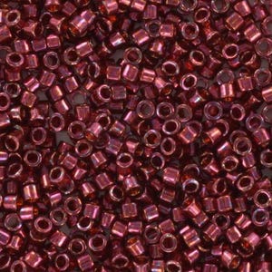 Peut inclure: Gros plan sur une grande quantité de petites perles de rocaille de couleur rouge foncé métallisé. Les perles sont cylindriques avec un petit trou au centre.