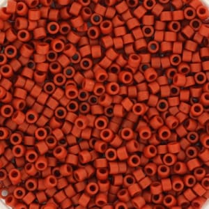 Pode incluir: Uma visão de perto de uma grande quantidade de pequenas contas redondas de cor laranja-avermelhada. As contas são de plástico e têm um acabamento fosco.