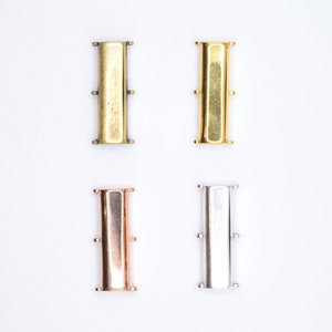 May include: Four metal connector pieces for jewellery making. The pieces are in four different finishes: antique brass, gold, rose gold, and silver.