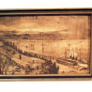 May include: A framed sepia-toned landscape artwork depicting a river scene with a steamboat docked near a tree-lined bank. The rectangular print features dark brown and cream hues, showcasing a vessel with smoke rising from its stacks.