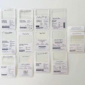 May include: A collection of travel-themed keepsake cards with various designs and text. Each card features a rectangular frame, with phrases like "Lisbon Journey" and "Let's Paris." The cards are white with black text and some include barcode-like elements.