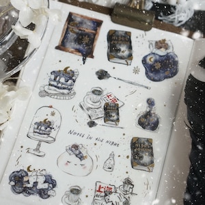 May include: A sticker sheet featuring various illustrations with a night theme, including a window, books labeled Night Journal, a person sleeping, cakes, a bottle, a cat, and coffee. The text Notes in the Night is printed in the center.