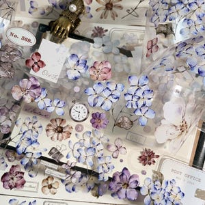 May include: Decorative floral washi tape featuring watercolor-style blue, purple, and pink flowers. The tape includes vintage-style elements like a pocket watch, labels, and the text "No. 369."