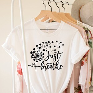 May include: White t-shirt with a black dandelion design and the text "Just Breathe".