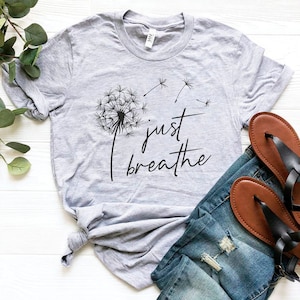 May include: A gray t-shirt with a black dandelion graphic and the text "just breathe".