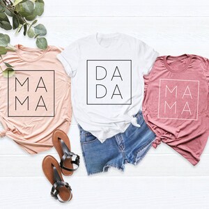 May include: Three t-shirts with the words "Mama", "Dada", and "Mama" printed on them. The shirts are in pink, white, and light pink.