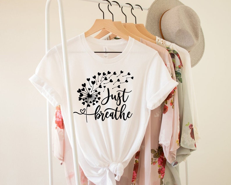 May include: White t-shirt with a black dandelion design and the text "Just Breathe".