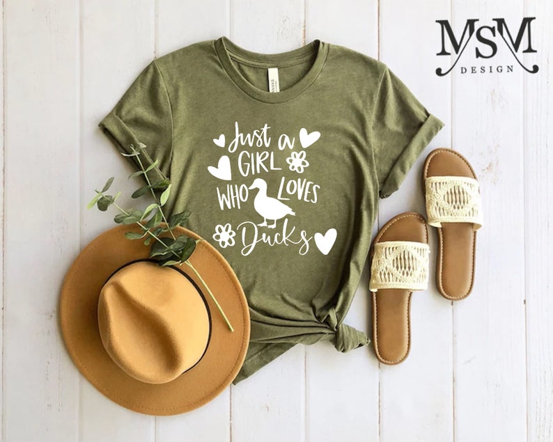 May include: Green t-shirt with white text that reads "Just a girl who loves ducks" with a duck silhouette and hearts.