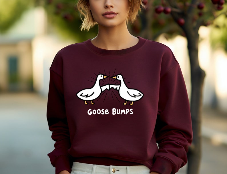 Puede incluir: Una sudadera color burdeos con un gr&aacute;fico blanco de dos gansos enfrentados con el texto "Goose Bumps" debajo.