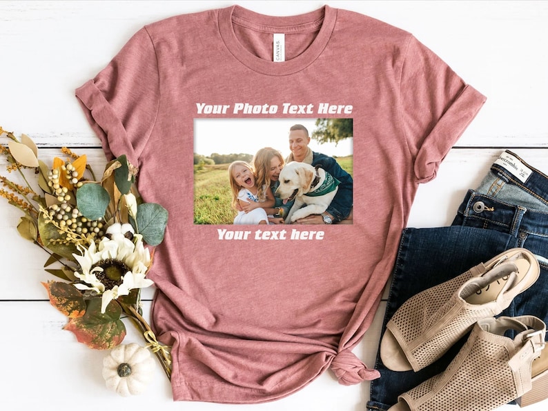 Może przedstawiać: R&oacute;żowa koszulka z nadrukiem w postaci ramki na zdjęcia. Ramka zawiera zdjęcie rodzinne z tekstem "Your Photo Text Here" i "Your text here". Koszulka jest stylizowana z dżinsami i sandałami.