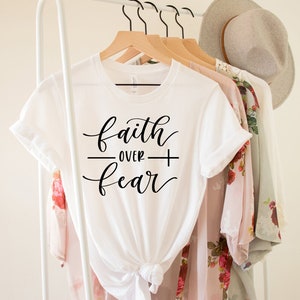 May include: White t-shirt with the text "faith over fear" written in black cursive script.