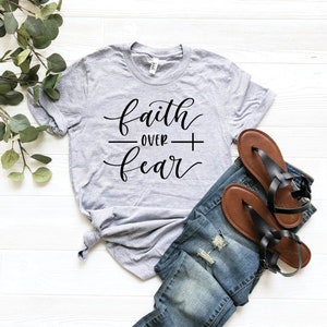 May include: A gray t-shirt with the text "faith over fear" in black cursive lettering.