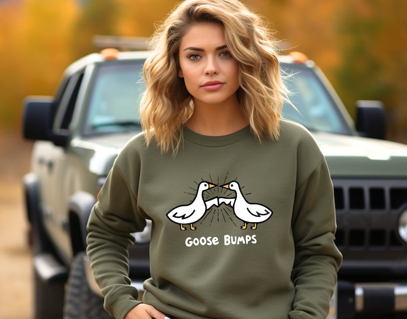 Puede incluir: Una sudadera verde con un gr&aacute;fico blanco de dos gansos que se miran con el texto "Goose Bumps" debajo.