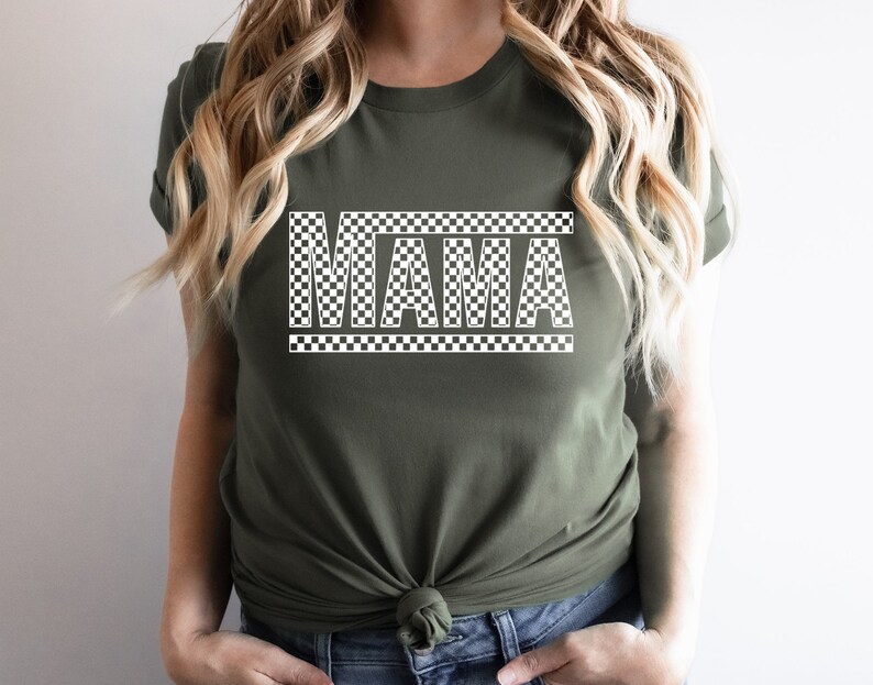 Puede incluir: Una camiseta verde oliva con la palabra "MAMA" en un patr&oacute;n blanco a cuadros. El texto est&aacute; centrado en la camiseta, con el dise&ntilde;o a cuadros que tambi&eacute;n delinea la palabra. Una prenda casual para el d&iacute;a a d&iacute;a.