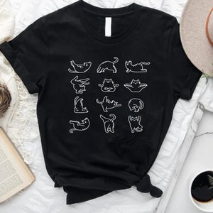 Op de afbeelding: Zwart T-shirt met een witte afbeelding van katten in verschillende yogaposes.