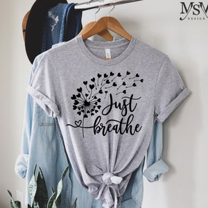 May include: Gray t-shirt with a black dandelion design and the text "Just breathe".