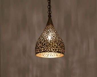 May include: A gold pendant light with a decorative, intricate, cut-out design. The light is hanging from a chain and is turned on, illuminating the room.