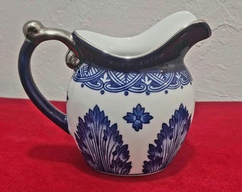 Jarra para crema Grace de la compañía Bombay, de porcelana azul cobalto con detalles plateados y decoración estilo chinoiserie.