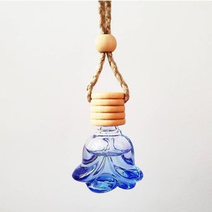 May include: A blue glass car air freshener shaped like a flower with a wooden cap and a natural fiber rope hanger.
